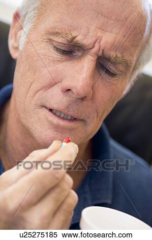 Stock Photography - Senior Man Holding Pill. Fotosearch