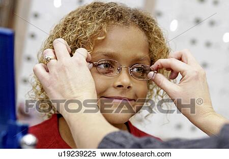 Stock Photography - African American girl trying on glasses. Fotosearch