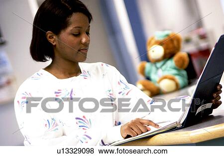 Stock Photo - African American nurse looking at patient chart. Fotosearch