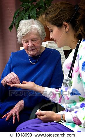 Stock Photo - Nurse giving senior woman a bottle of pills. Fotosearch
