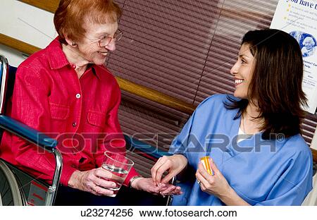 Stock Photograph - Nurse giving senior woman pills. Fotosearch