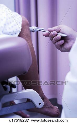 Stock Photo - Physician checking patients reflexes. Fotosearch