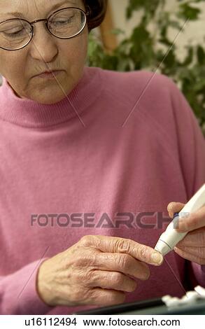 Picture - Woman checking blood sugar. Fotosearch