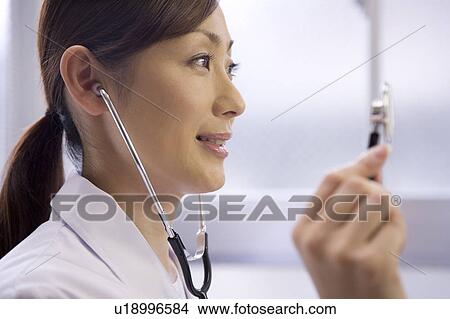 Picture - A female doctor examining patient with stethoscope. Fotosearch