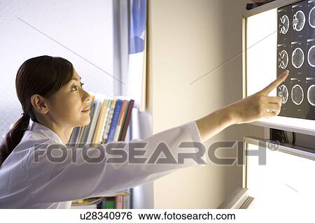 Stock Photograph - A female doctor examining X-ray image. Fotosearch