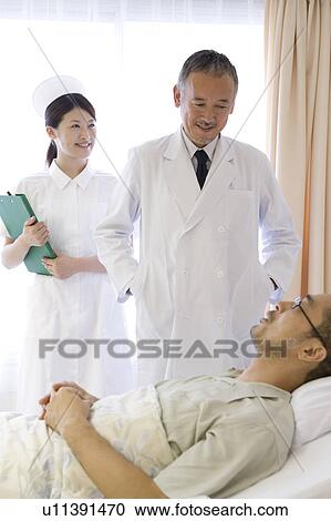Doctor and nurse talking to patient in bed View Large Photo Image Stock Image - Doctor and nurse talking to patient in bed. Fotosearch