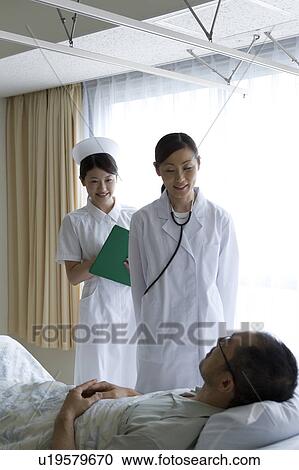 Doctor and nurse talking to patient in bed View Large Photo Image Stock Image - Doctor and nurse talking to patient in bed. Fotosearch