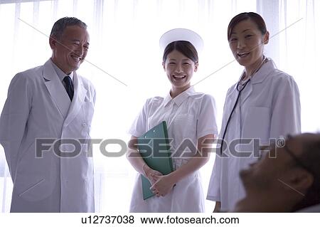 Doctors and nurse talking to patient in bed View Large Photo Image Stock Photo - Doctors and nurse talking to patient in bed. Fotosearch