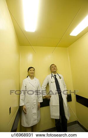 Stock Image - Doctors standing in elevator. Fotosearch