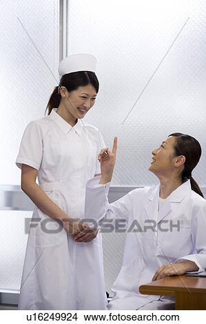 Picture - Female doctor and nurse talking. Fotosearch