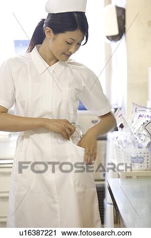 Stock Image - Female nurse checking pocket. Fotosearch