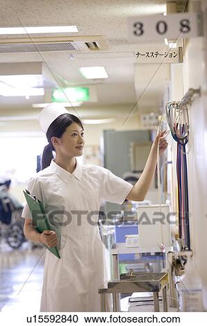 Stock Image - Female nurse checking stethoscopes at nurse station. Fotosearch