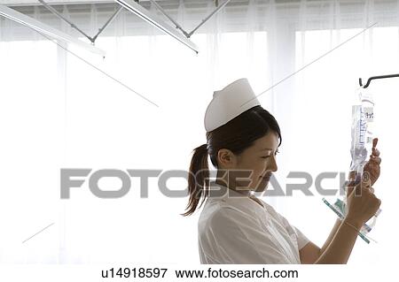 Stock Photo - Female nurse preparing intravenous drip. Fotosearch