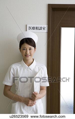 Stock Photo - Female nurse standing in front of door. Fotosearch