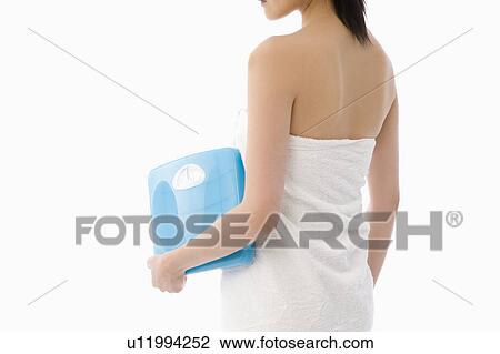 Stock Image - Woman holding bathroom scale. Fotosearch