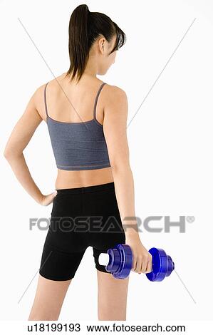 Stock Image - Woman holding dumbbell, rear view. Fotosearch