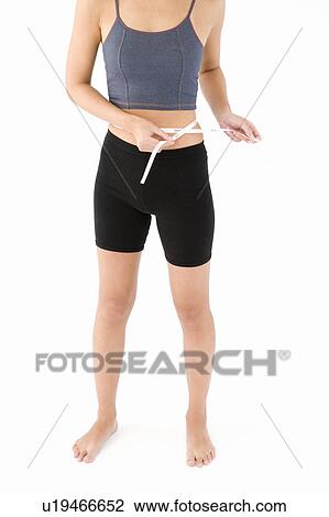 Stock Image - Woman measuring her waist. Fotosearch