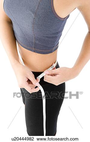 Stock Image - Woman measuring her waist. Fotosearch