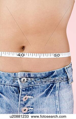 Stock Image - Woman measuring her waist. Fotosearch