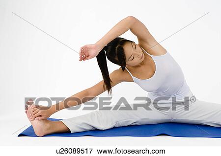 Stock Photo - Woman sitting on floor stretching. Fotosearch