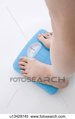 Stock Photography - Woman standing on bathroom scale. Fotosearch