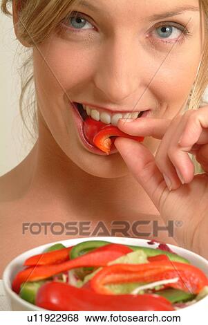 Stock Photo - Close-up of Woman eating red pepper. Fotosearch