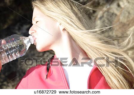 Female jogger drinking from water bottle, side view View Large Photo Image Stock Photo - Female jogger drinking from water bottle, side view. Fotosearch