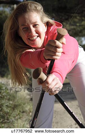 Stock Image - Female Nordic Walker doing stretching exercise. Fotosearch