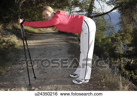 Stock Photograph - Female Nordic Walker doing stretching exercise. Fotosearch