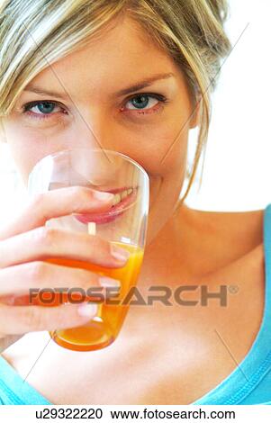 Stock Image - Portrait of woman drinking orange juice. Fotosearch