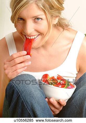 Stock Photography - Woman eating red pepper. Fotosearch