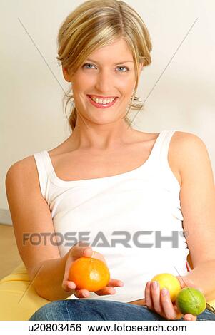 Stock Photograph - Woman holding citrus fruit. Fotosearch