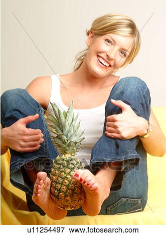 Stock Photo - Woman holding pineapple with her feet. Fotosearch