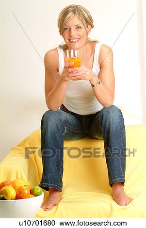 Stock Image - Woman on sofa drinking juice. Fotosearch
