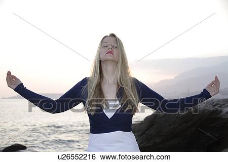 Woman standing at a rocky sea coast, meditating View Large Photo Image Stock Photograph - Woman standing at a rocky sea coast, meditating. Fotosearch
