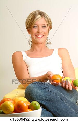 Stock Image - Woman with bowl of citrus fruit in foreground. Fotosearch