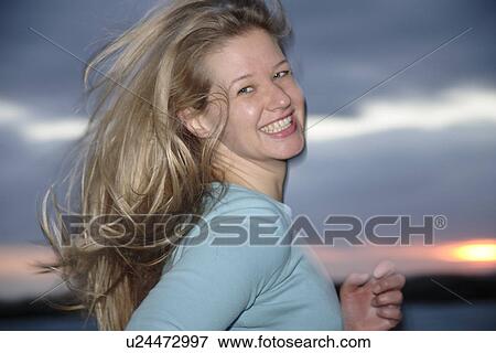 Stock Photo - Young blond woman jogging at the beach, portrait. Fotosearch