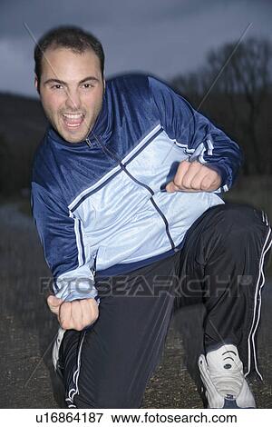 Young man in a sweat suit jacket cheering in front of dark clouds View Large Photo Image Stock Photo - Young man in a sweat suit jacket cheering in front of dark clouds. Fotosearch