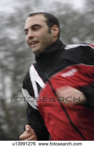 Stock Photograph - Young man jogging in the park, front view. Fotosearch