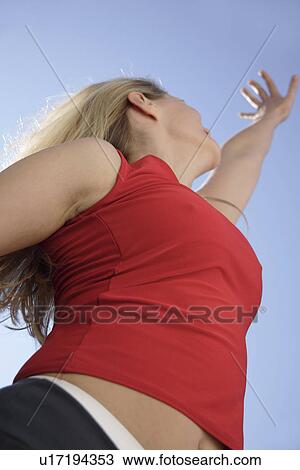 Young woman with arms stretched out in front of blue sky, low angle view View Large Photo Image Stock Image - Young woman with arms stretched out in front of blue sky, low angle view. Fotosearch