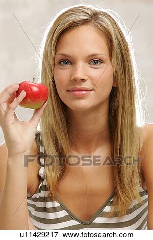 Young woman with long blond hair eating an apple, portrait View Large Photo Image Stock Photo - Young woman with long blond hair eating an apple, portrait. Fotosearch