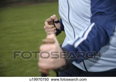 Stock Image - Male Nordic walker, close up of hands and pole straps. Fotosearch