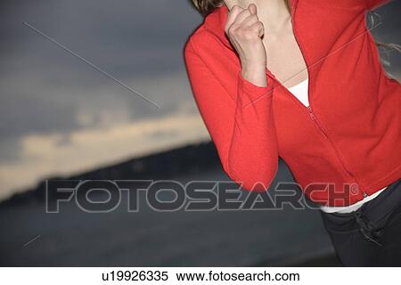 Stock Photography - Upper part of woman's body jogging at the beach, side view. Fotosearch