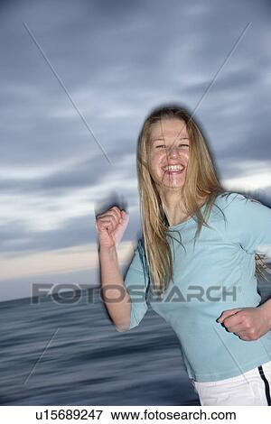 Stock Photo - Young blond woman jogging at the beach, side view. Fotosearch