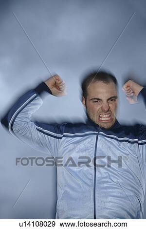 Young man in a sweat suit jacket cheering in front of dark clouds View Large Photo Image Stock Photo - Young man in a sweat suit jacket cheering in front of dark clouds. Fotosearch