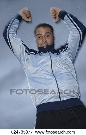 Young man in a sweat suit jacket cheering in front of dark clouds View Large Photo Image Stock Photo - Young man in a sweat suit jacket cheering in front of dark clouds. Fotosearch