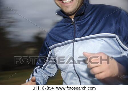 Picture - Young man jogging in spite of bad weather. Fotosearch