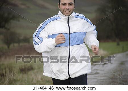 Stock Photograph - Young man jogging in spite of bad weather. Fotosearch