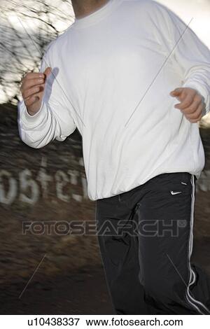 Stock Photo - Young man jogging on a street on a rainy day. Fotosearch