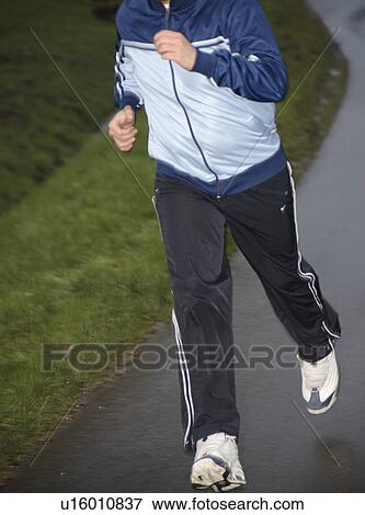 Stock Photo - Young man jogging on a street on a rainy day. Fotosearch